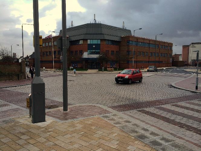 A photograph showing a paved promenade area with new street furniture and a large brick leisure centre building in the background.