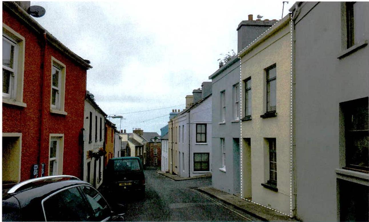 A street-level photograph showing a row of terraced houses with a white dashed line outlining a building on the right side, likely indicating a proposed extension or boundary.