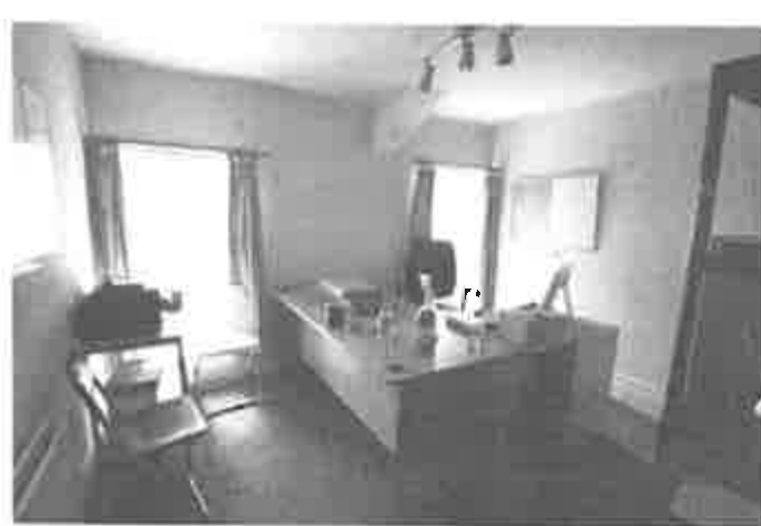 A black and white interior photograph showing the bar area of a public house with a counter, seating, and windows.