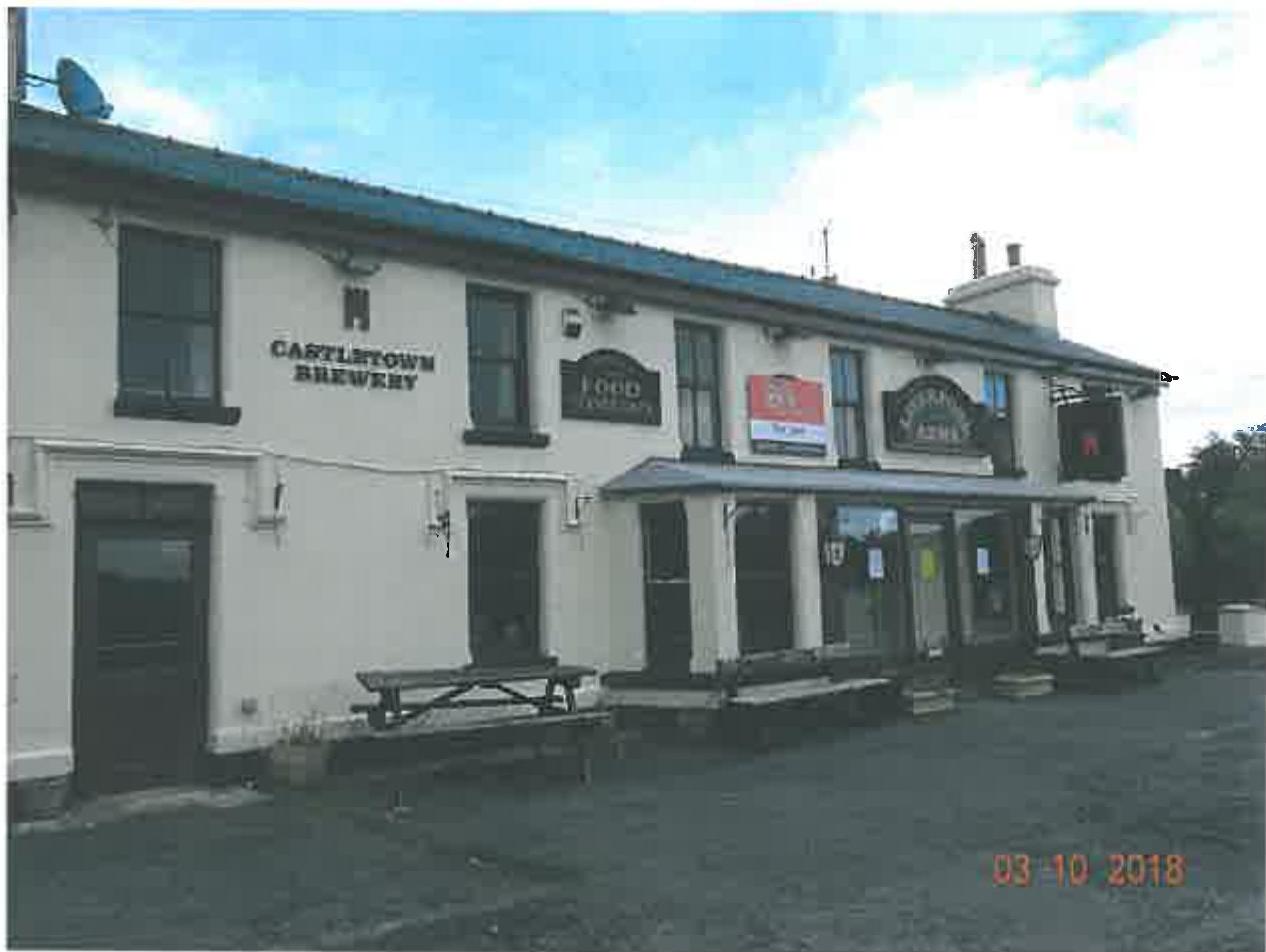 A street-level photograph of a white two-story public house featuring 'Castletown Brewery' signage and outdoor picnic tables.