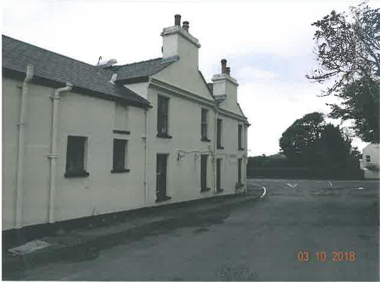 A photograph showing the exterior elevation of a long, white-washed building with multiple chimneys, likely a former public house or terrace of cottages.