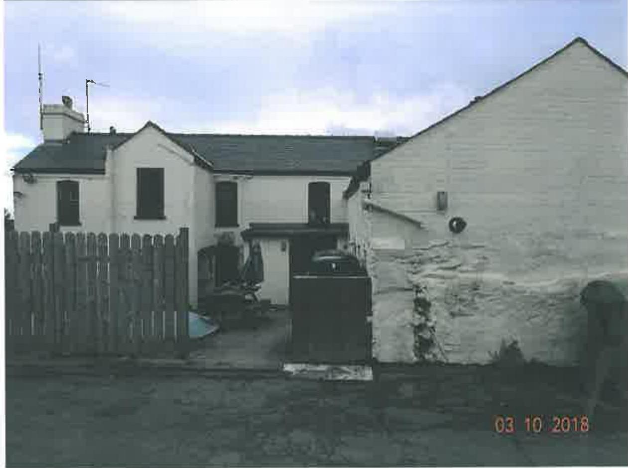 A photograph showing the exterior of a white two-story building and an adjacent large white outbuilding, likely the former public house.