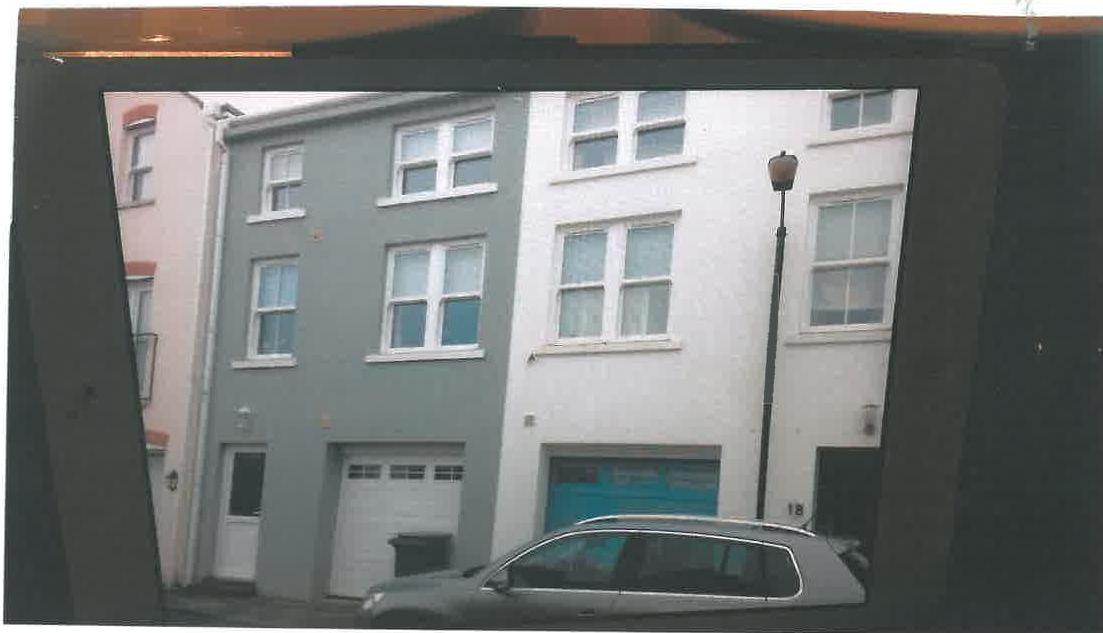 A photograph showing the front elevation of a terraced building with white PVC windows and a garage door.