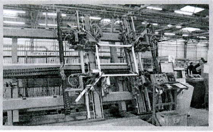 A grainy black and white photograph showing large industrial machinery, possibly a press, inside a workshop or factory interior.