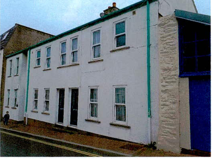 A street-level photograph showing the exterior elevation of a white, two-story terraced building with white sash windows and green downpipes.