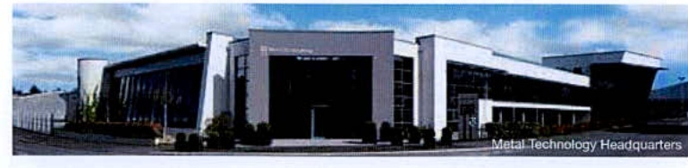 A low-resolution exterior view of a modern white commercial building identified as 'Metal Technology Headquarters'.