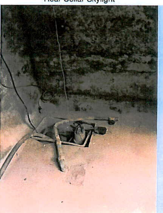 A grainy photograph showing a floor opening with pipes, labeled 'Rear Cellar Skylight' at the top.