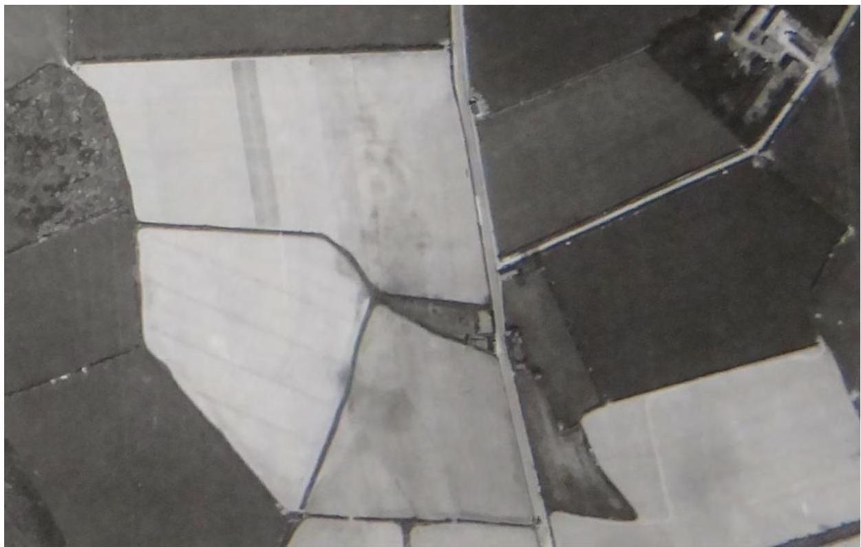 Black and white aerial photograph showing a rural landscape with agricultural fields divided by hedgerows and walls.