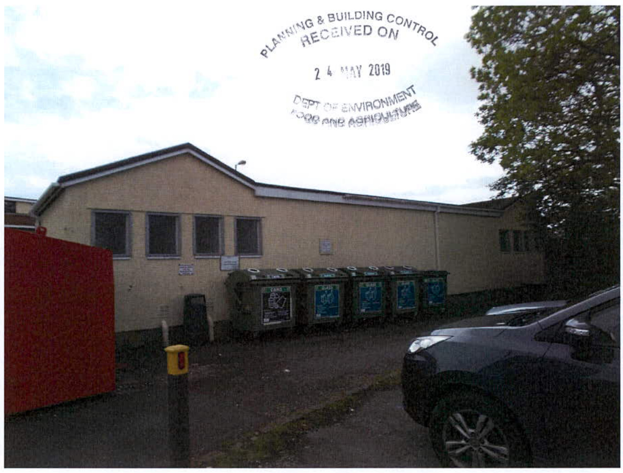 A photograph showing the exterior of a single-story, light-colored building with a row of recycling bins, overlaid with a planning authority receipt stamp.