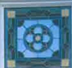 A close-up photograph of a decorative stained glass window featuring a blue and green geometric pattern.