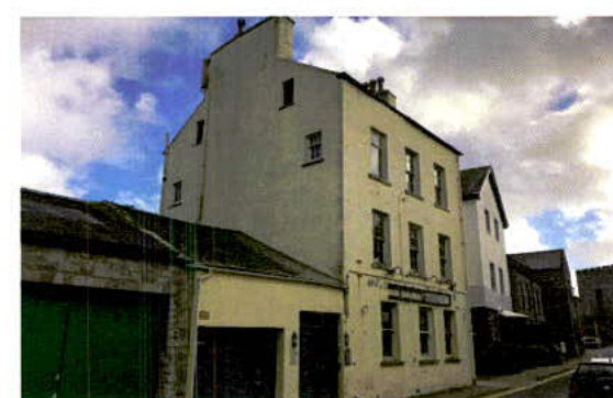 A street-level photograph of a white, multi-story building, likely a former public house, featuring a lower single-story extension on the left side.