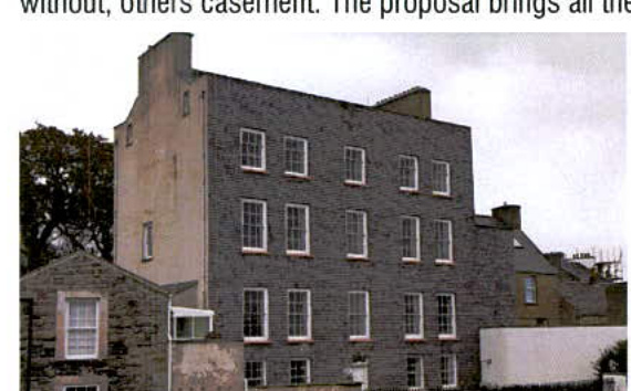 A photograph of a multi-story grey stone building, likely a former public house, showing its front elevation with sash windows.
