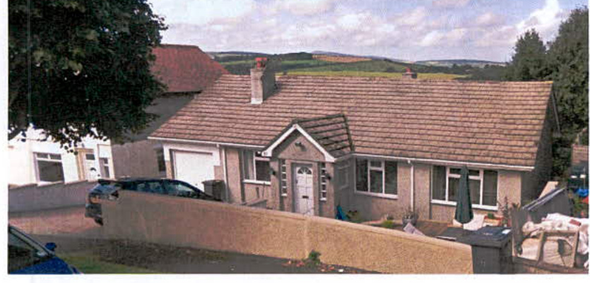 A photograph showing the exterior of a single-story detached bungalow with a tiled roof and attached garage.