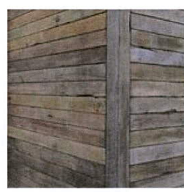 A close-up photograph showing weathered horizontal wooden cladding and a vertical corner post, likely depicting an existing outbuilding or extension side elevation.