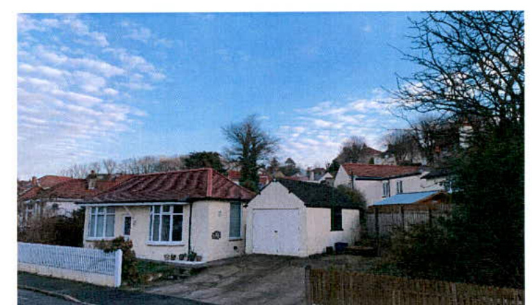 A photograph showing a white single-story bungalow with a red tiled roof and an attached white garage.