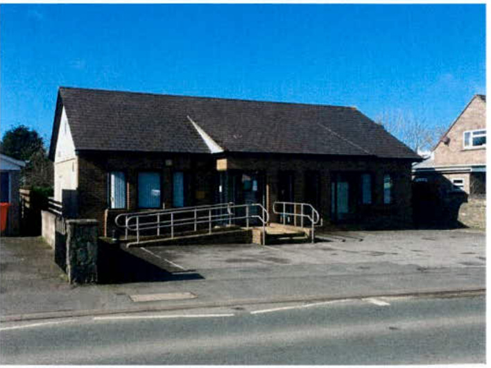 A photograph showing the exterior of a single-story commercial building with a pitched roof and a disabled access ramp leading to the entrance.