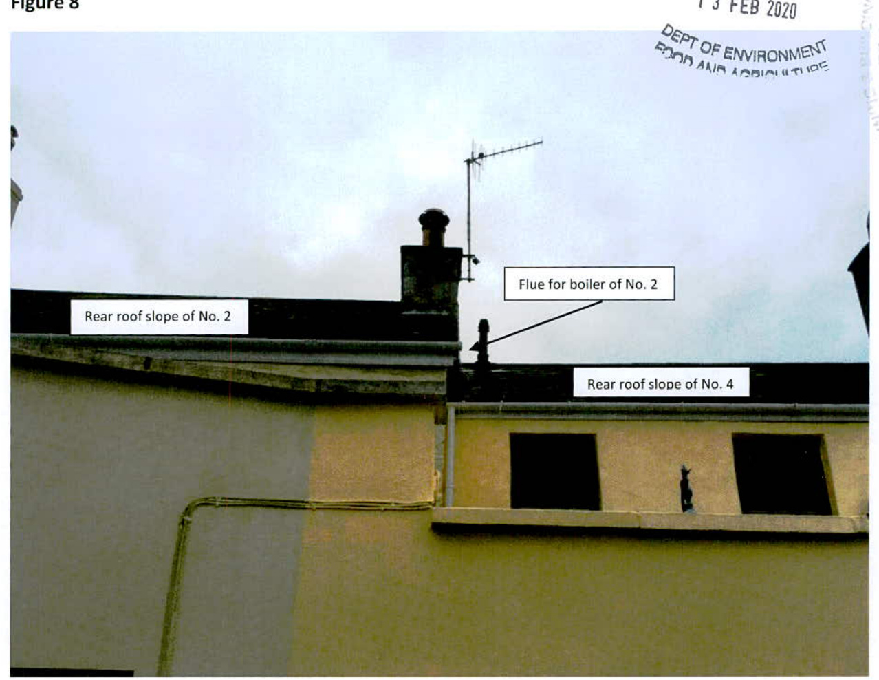 Annotated photograph showing the rear roof slopes and chimney of adjacent properties, highlighting a proposed boiler flue location.