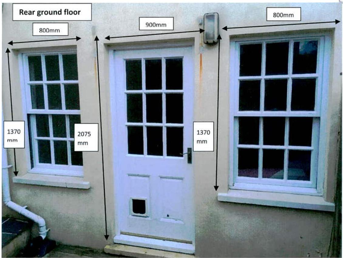 Photograph of a rear ground floor facade featuring a central door and two sash windows, annotated with dimensional measurements.