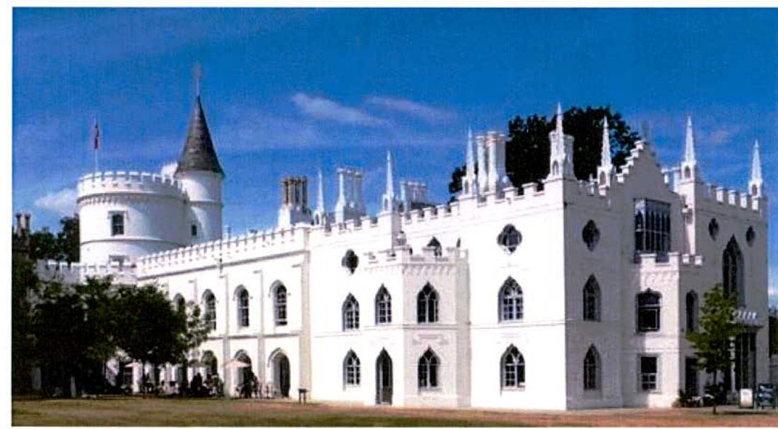 A photograph of a large, white, castle-like historic building featuring turrets, crenellations, and Gothic-style windows under a blue sky.