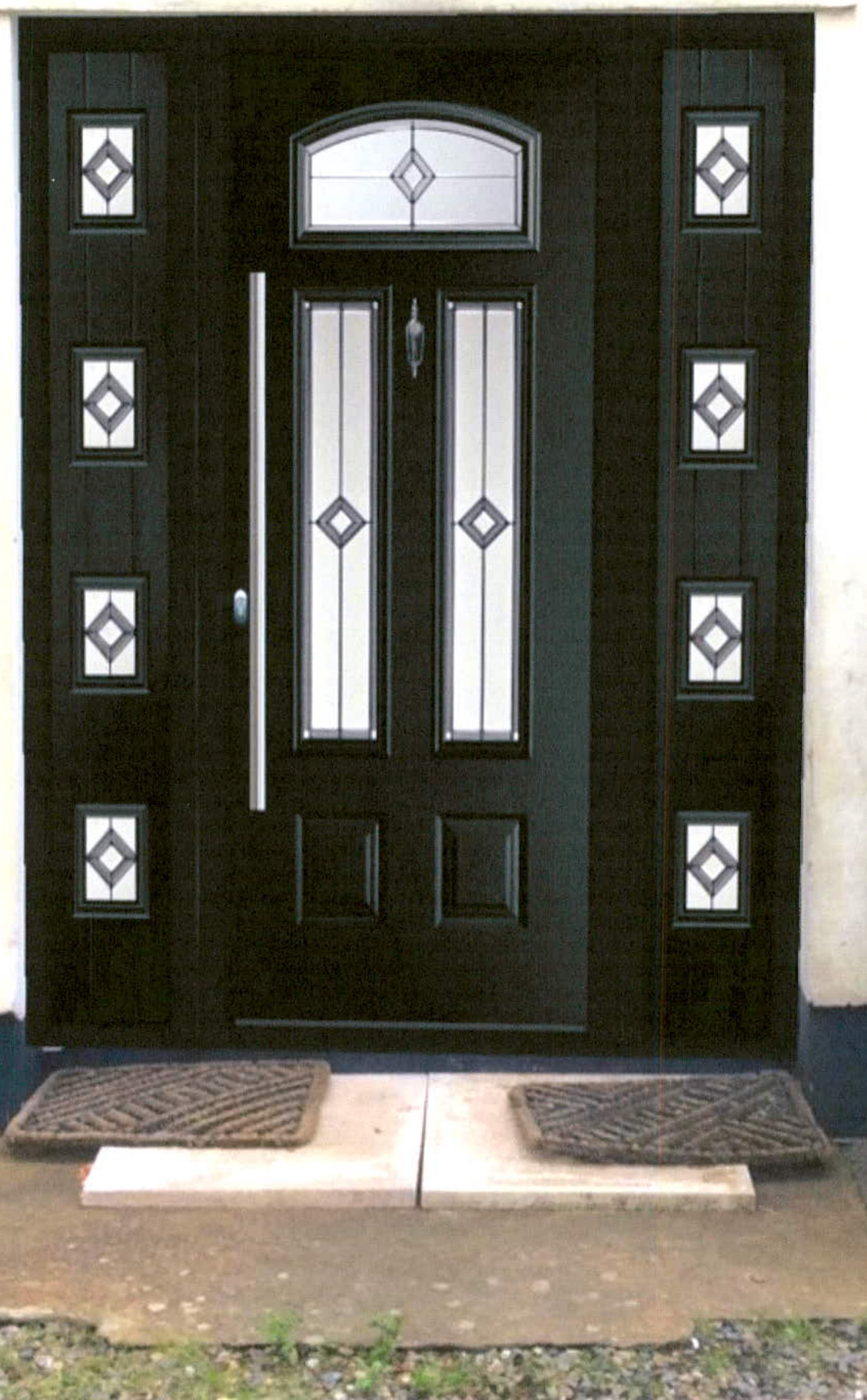 A close-up photograph of a black front door featuring decorative diamond-patterned glass panels and matching sidelights.