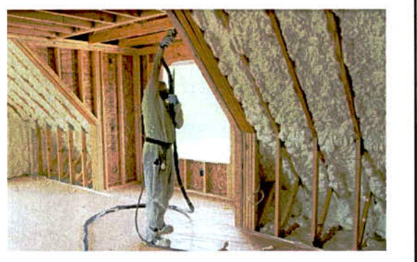A photograph showing a worker in protective gear spraying foam insulation onto the wooden rafters of an attic space during construction.
