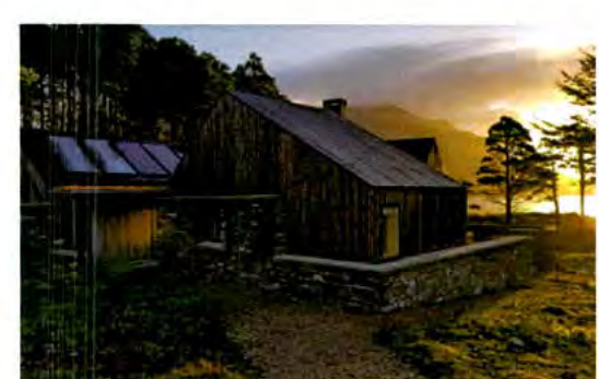 A photograph showing a rural building, likely a barn conversion, featuring a modern extension with solar panels on the roof.