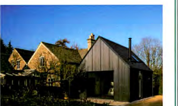 A photograph showing a traditional stone building adjacent to a modern, dark-clad structure with a steep pitched roof.