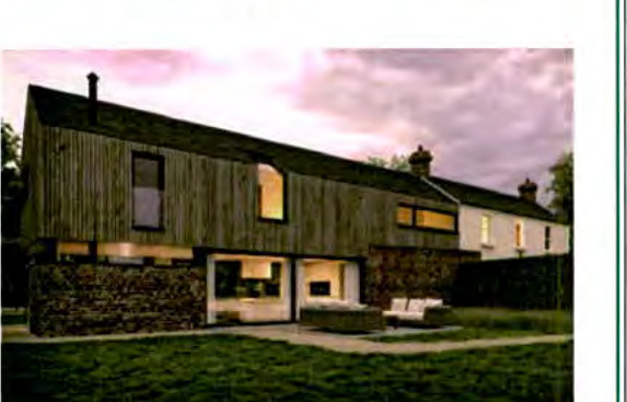 The image shows a modern two-storey extension with vertical timber cladding and a stone base attached to an existing white residential building.