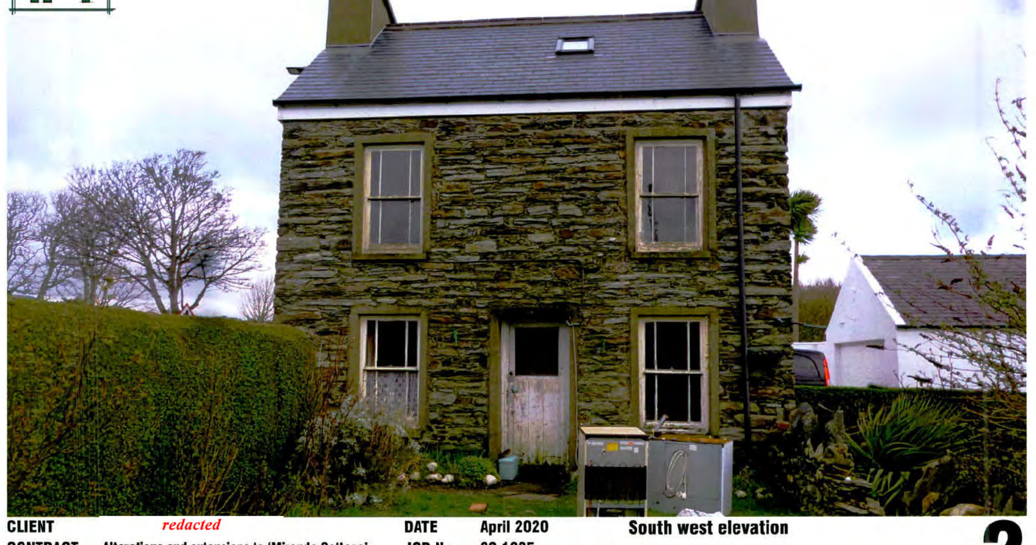 A photograph showing the existing two-story stone dwelling, specifically the south-west elevation, featuring a slate roof, chimneys, and surrounding hedges.