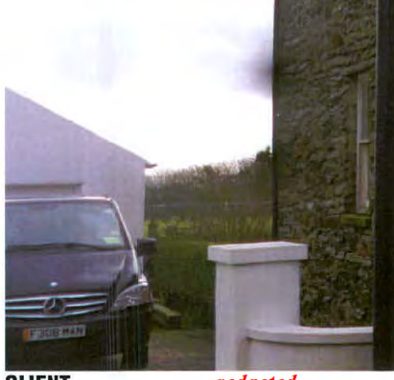 A photograph showing a white single-storey structure on the left with a car parked in front, adjacent to a stone wall of an existing building on the right, with a rural field in the background.