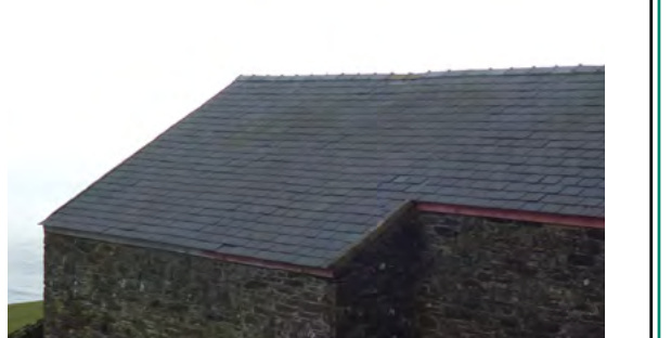 A close-up photograph showing the slate roof and stone wall of a rural building, likely an existing barn or outbuilding.