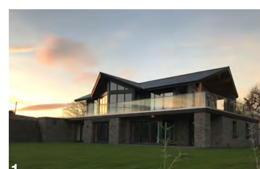 A visualisation of a modern two-story detached house featuring stone cladding and a large upper-level balcony with glass railings.