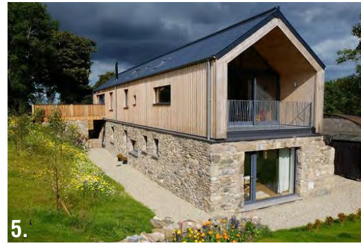 A photograph of a modern two-storey dwelling featuring a stone ground floor and timber-clad upper level with a balcony.
