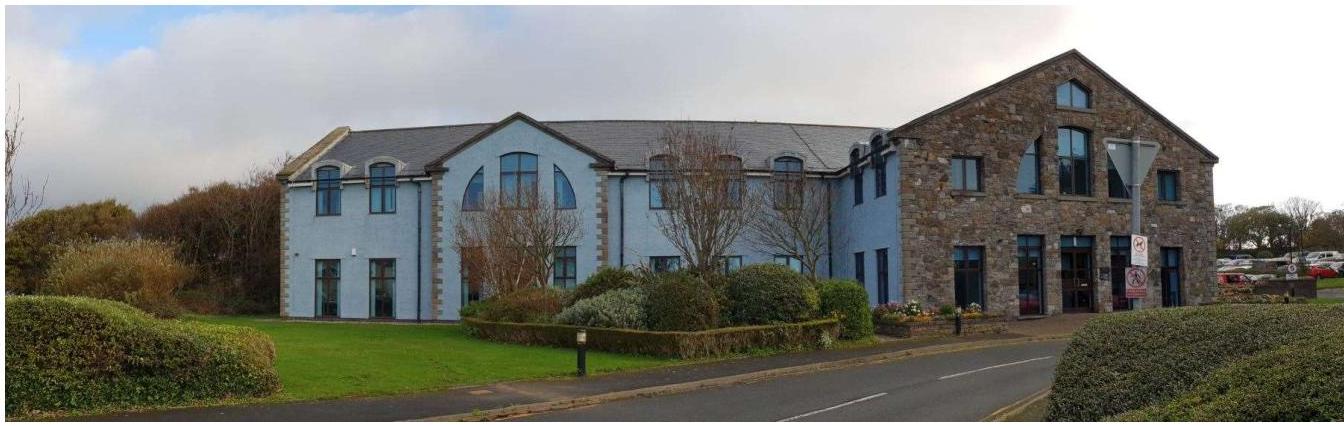 A wide-angle photograph showing the exterior of a large, modern commercial building with mixed stone and light blue rendered facades.