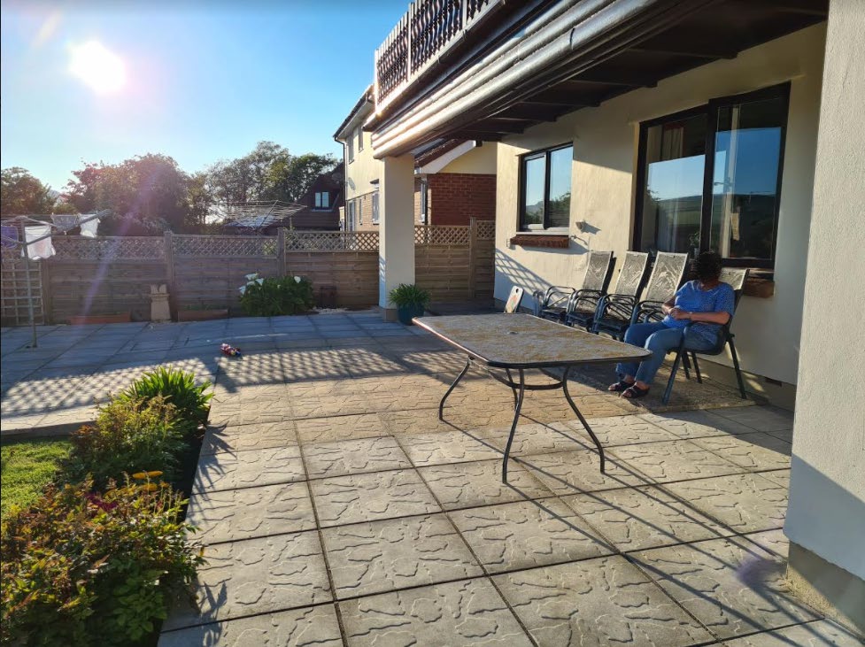 Photograph showing the existing rear patio and garden area with wooden fencing and a covered porch.