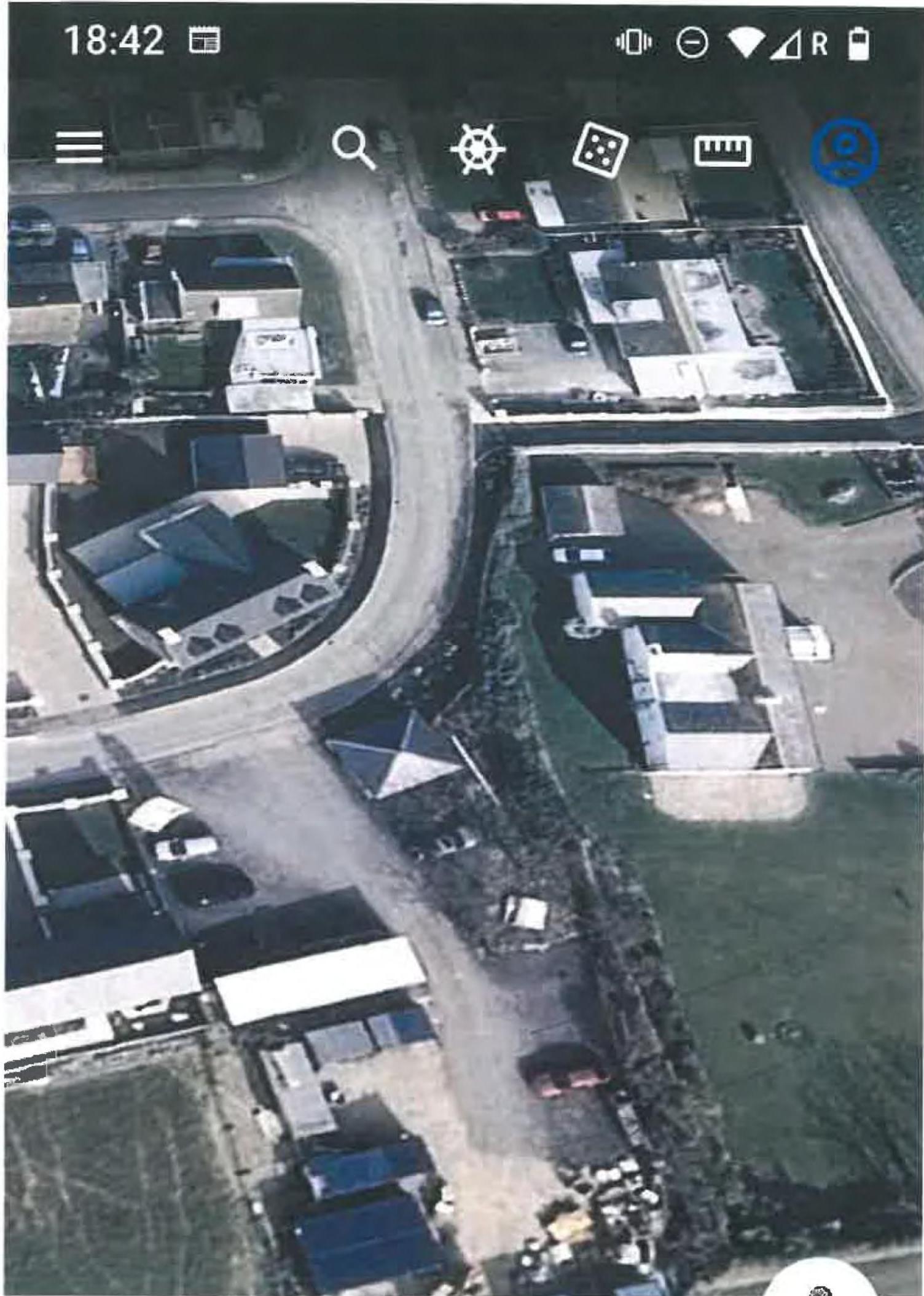 Aerial screenshot of a residential area showing a road junction, houses, and driveways.