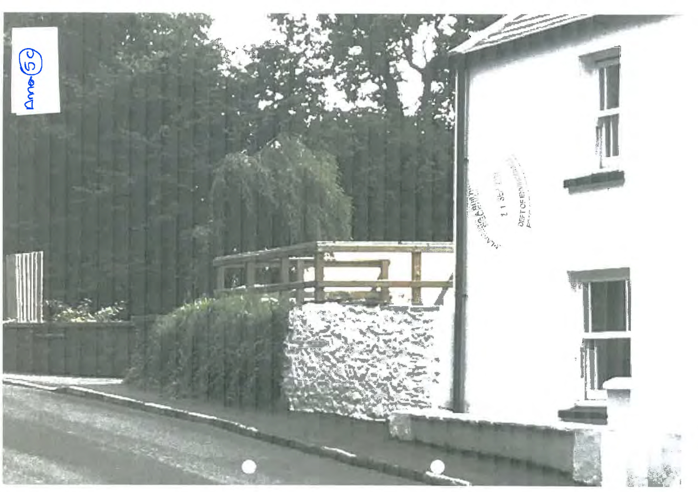 A photograph showing the side elevation of a white building with a newly constructed wooden raised deck structure attached to it.