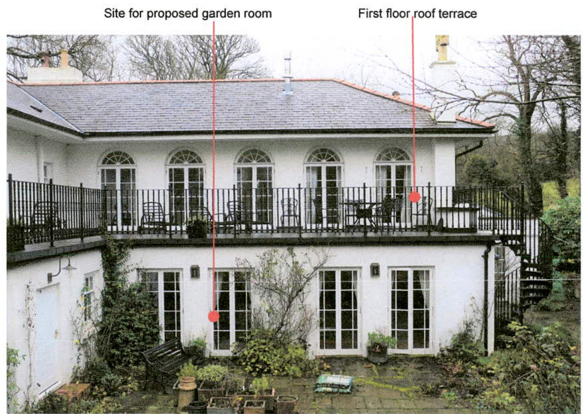 A photograph of the rear elevation of a white two-story house annotated with red lines and text indicating a proposed garden room and roof terrace.