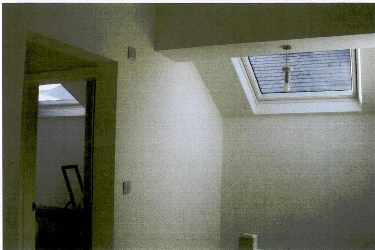 Interior photograph showing a room with a skylight window and a doorway leading to another room.
