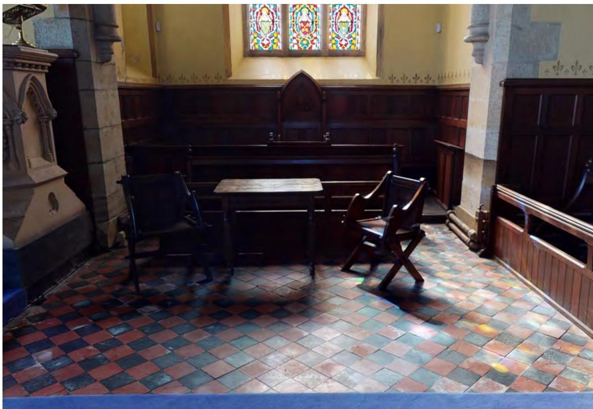 Interior photograph of a historic chapel featuring stained glass windows, wooden paneling, and a checkered tiled floor.