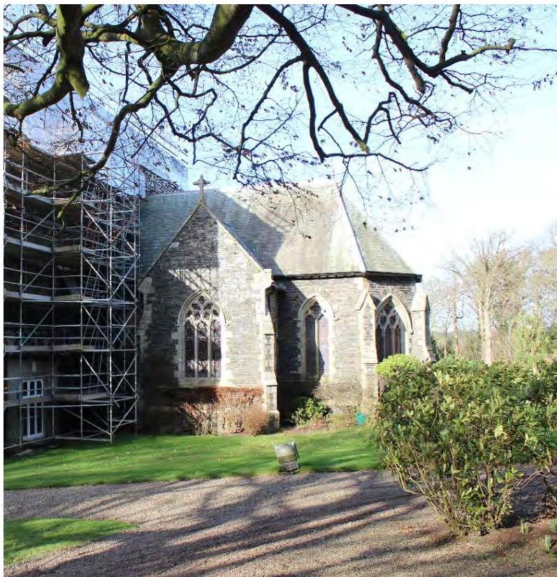 Exterior photograph of a stone chapel with Gothic windows and scaffolding erected on the adjacent wing.