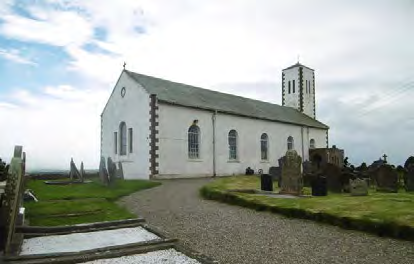 A photograph showing a white church building with a tower and a graveyard in the foreground.