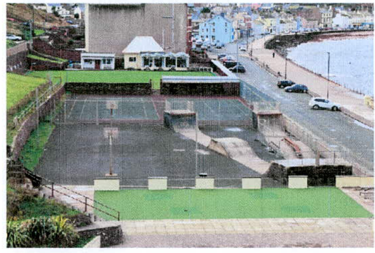 A photograph showing an outdoor recreational area with a skate park and sports court situated next to a coastal road and the sea.