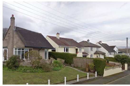 A street-level photograph showing a detached stone bungalow on the left followed by a row of other residential houses.