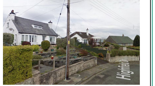 A street-level photograph showing a white detached house with a slate roof and dormer window, situated next to a road labeled Highfield Dr.