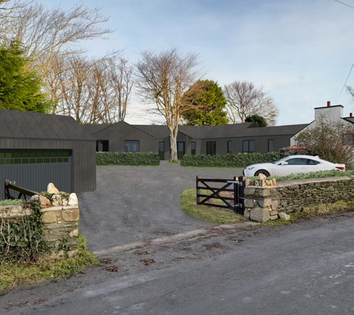 A photograph of a rural property featuring a large, dark-clad building complex resembling a converted barn and a separate detached garage structure to the left.