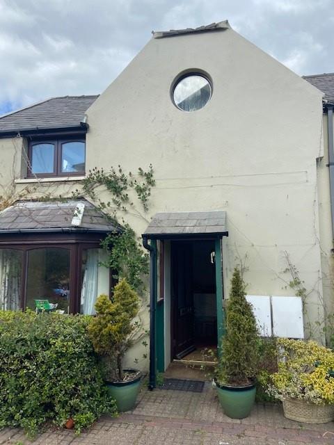 Exterior photograph of a white rendered residential building featuring a distinctive circular window near the roof peak and a porch area.
