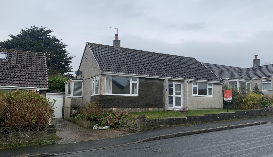 A street-level photograph showing the front elevation of a single-story detached bungalow with a tiled roof and a 'SOLD' sign in the garden.