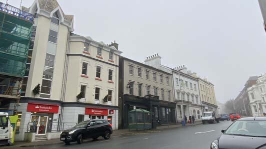 A street-level photograph showing a row of commercial buildings, including a building with a black ground floor facade and canopy, and a Nationwide bank branch.