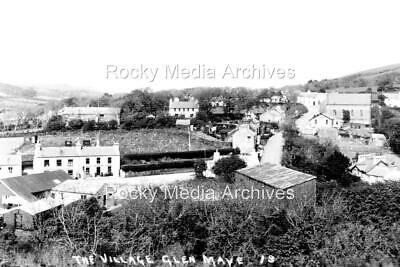 A black and white archival photograph showing a village landscape with buildings and hills, captioned 'The Village Glen Maye, I.O.M.'